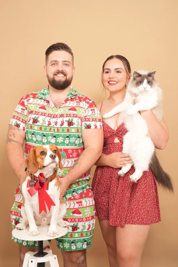 A man and woman posing with a dog and a cat