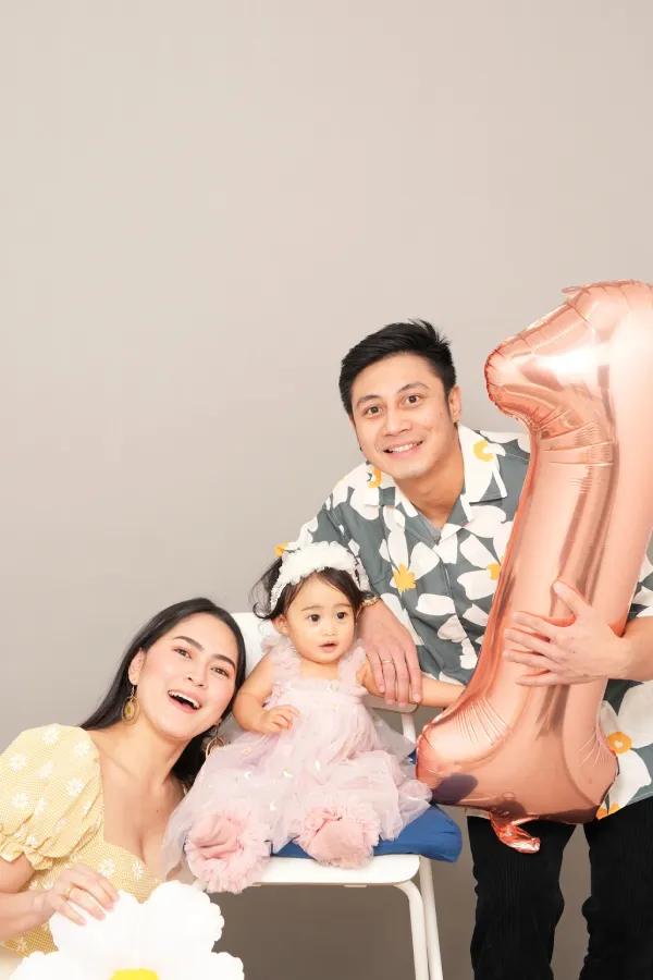 A woman, man and a little girl posing with a large 1 shaped balloon